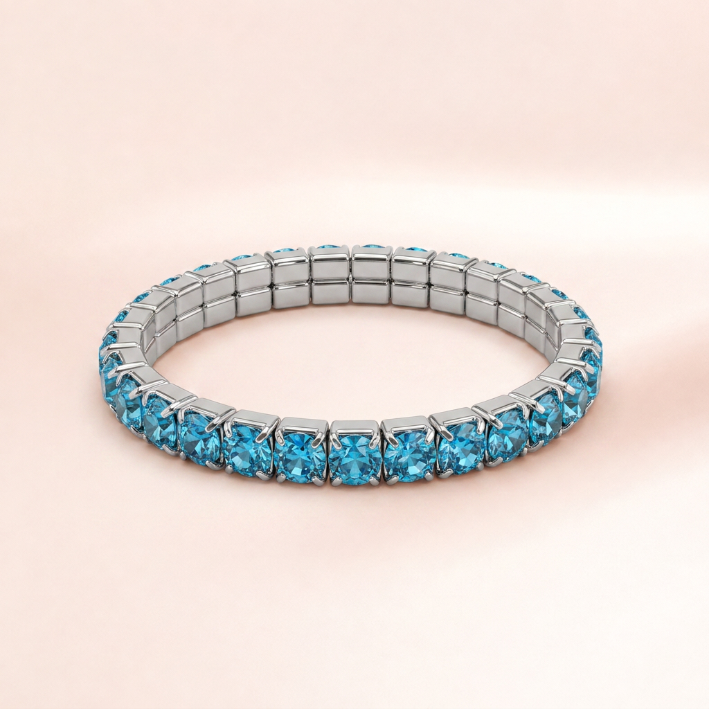 A silver-toned tennis bracelet set with round-cut light blue gemstones, displayed on a soft, pale pink background.