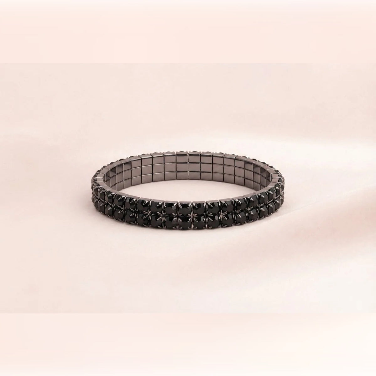 A black magnetic stretch bracelet with a textured, star-like pattern on the front, displayed on a soft beige background.