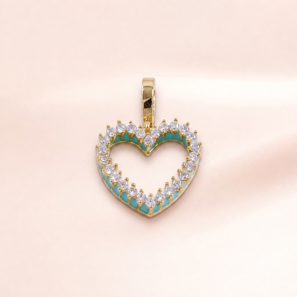 A gold heart-shaped pendant charm with a turquoise enamel inlay and clear round-cut stones, shown on a soft pink background.