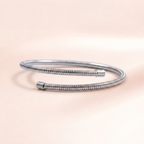 A silver metallic snake-style bangle bracelet with a textured, ribbed outer surface and smooth cylindrical end caps, photographed on a soft peach-pink background.