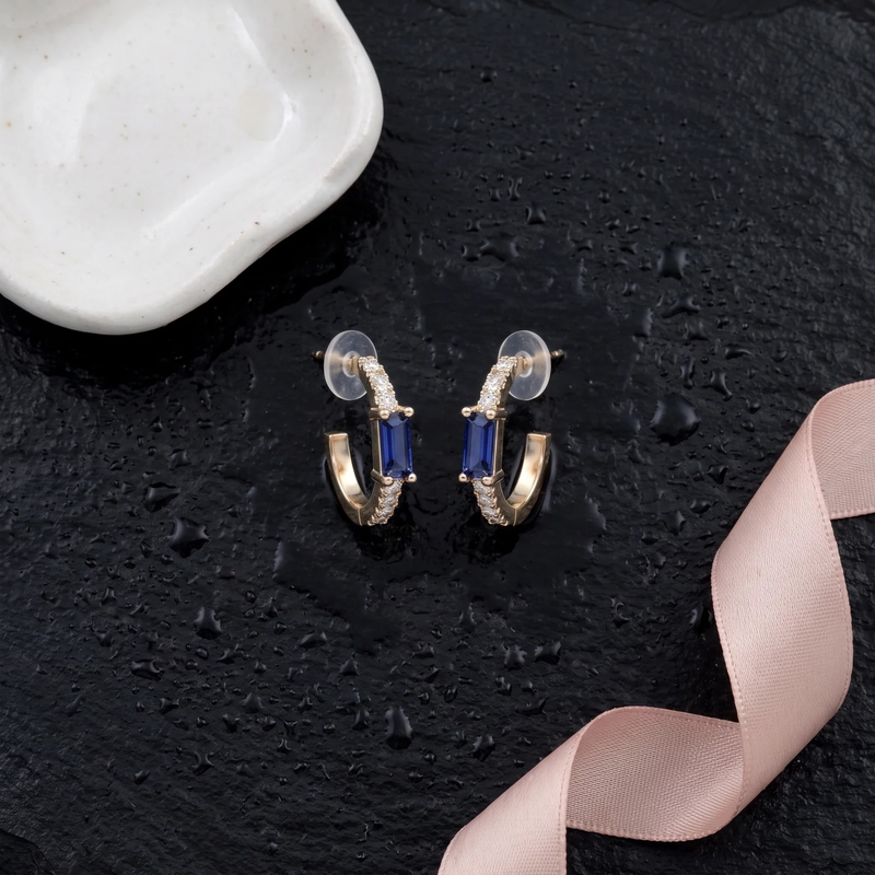 Flat lay of Gold Sapphire Baguette Huggie Earrings