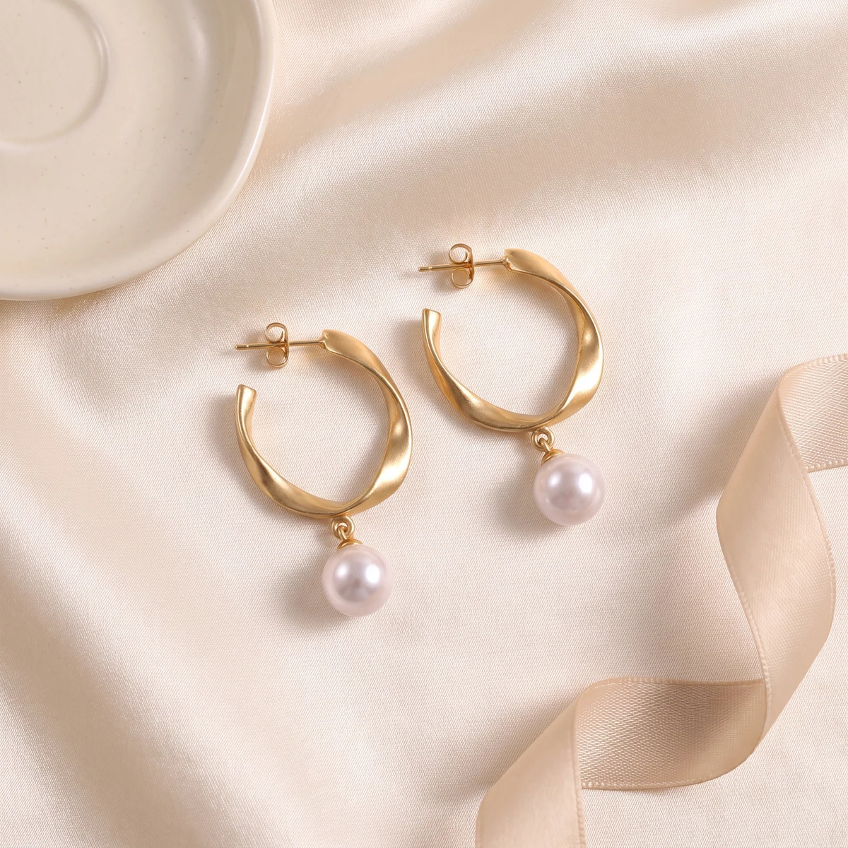 Flat lay of Twisted Gold Hoop Pearl Drop Earrings