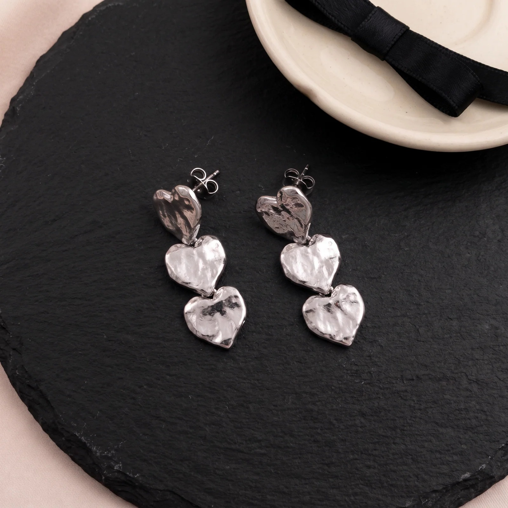 Flat lay of Triple Heart Drop Earrings