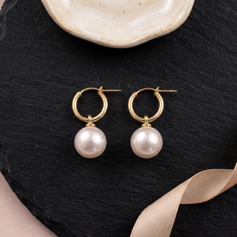 Flat lay of Gold Pearl Huggie Hoop Earrings