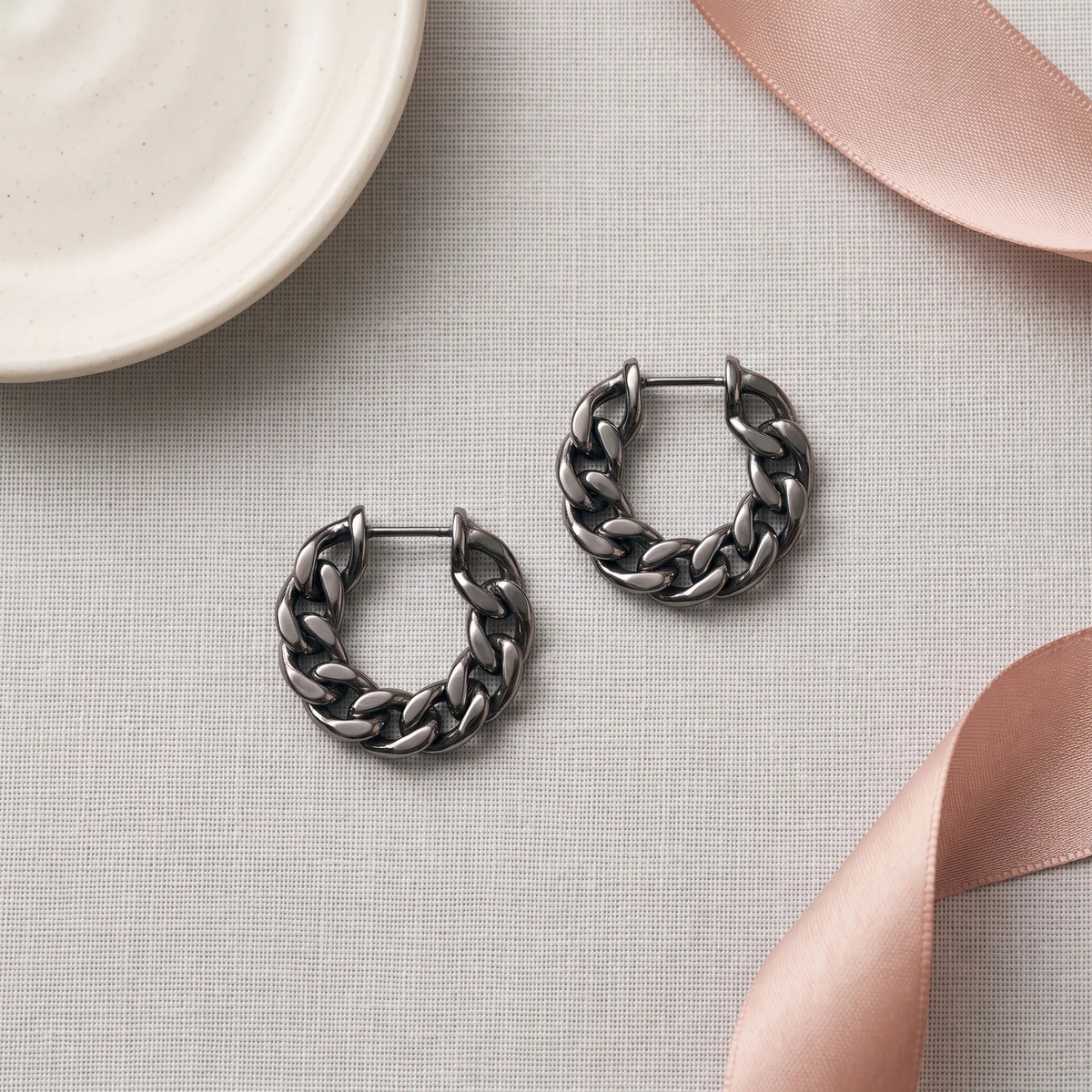 Flat lay of Silver Woven Chain Huggie Hoop Earrings