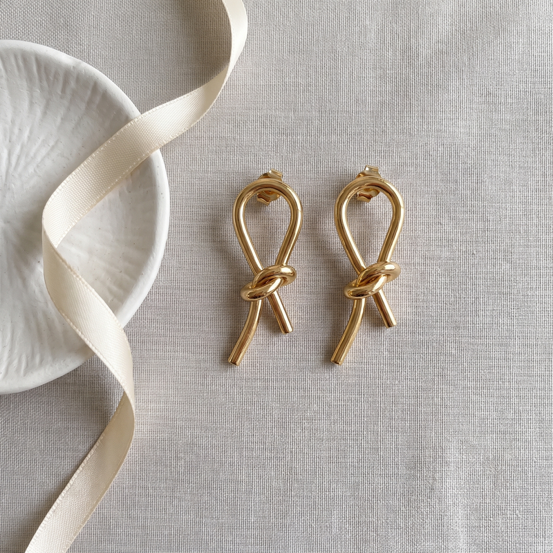 Flat lay of Gold Knot Drop Earrings